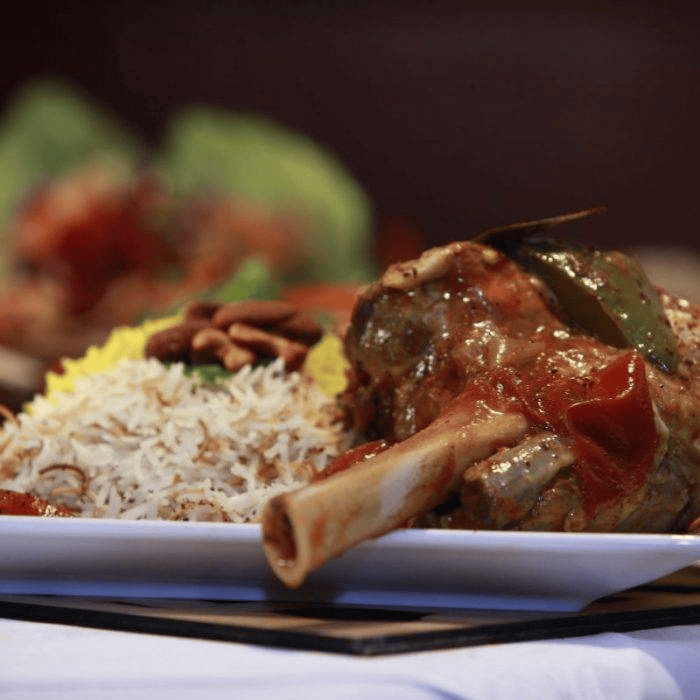 Authentic Lebanese slow-cooked lamb shank (Koussa or Lamb Ouzi) served with aromatic rice at Lebanese Village restaurant.