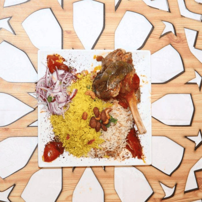 Lebanese Village braised lamb shank served with dual aromatic rice and toasted nuts dish.