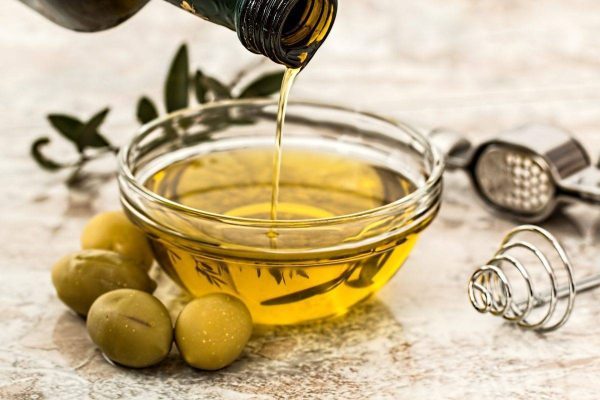 Premium extra virgin olive oil pouring into a glass dish for authentic Lebanese and Mediterranean cooking.
